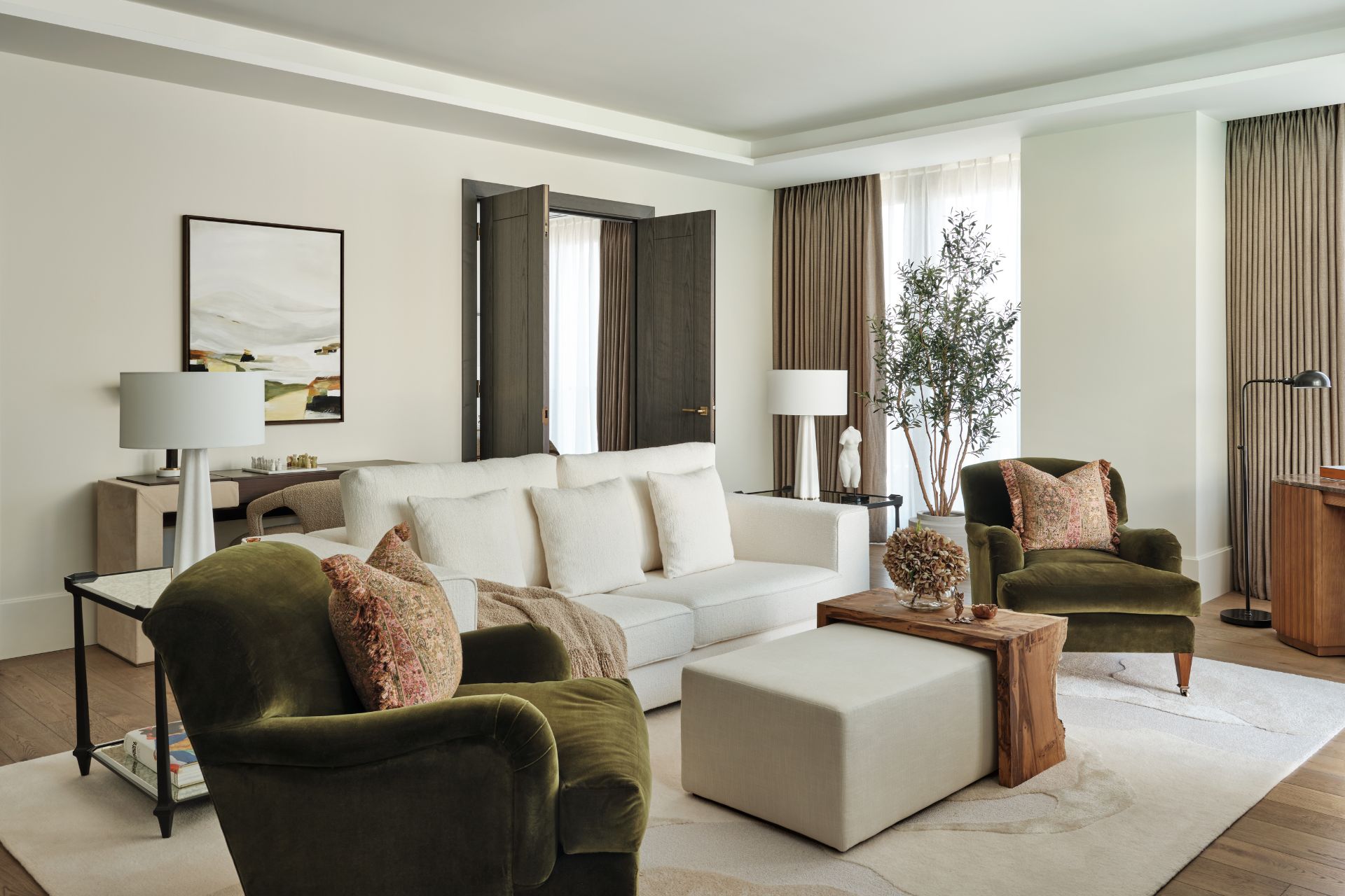 Living room with cream sofas and forest green velvet chairs.