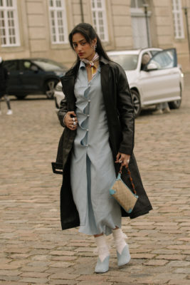 Woman wearing blue summer dress with autumn coat