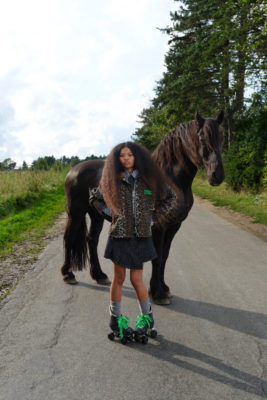 Woman in leopard print coat stood in front of horse