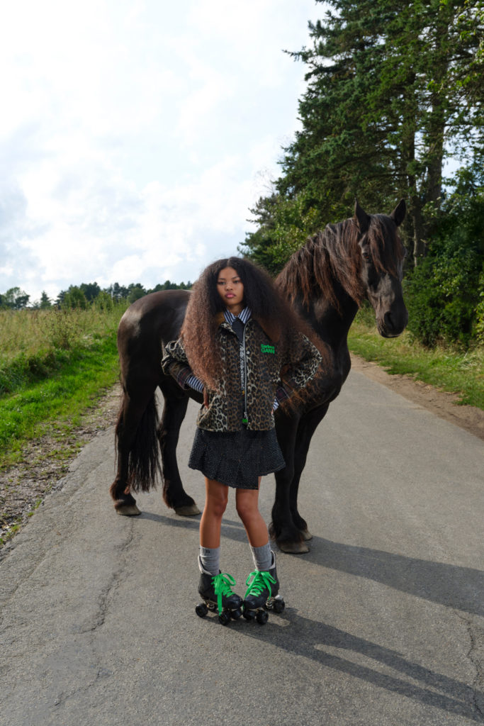 Woman in leopard print coat stood in front of horse