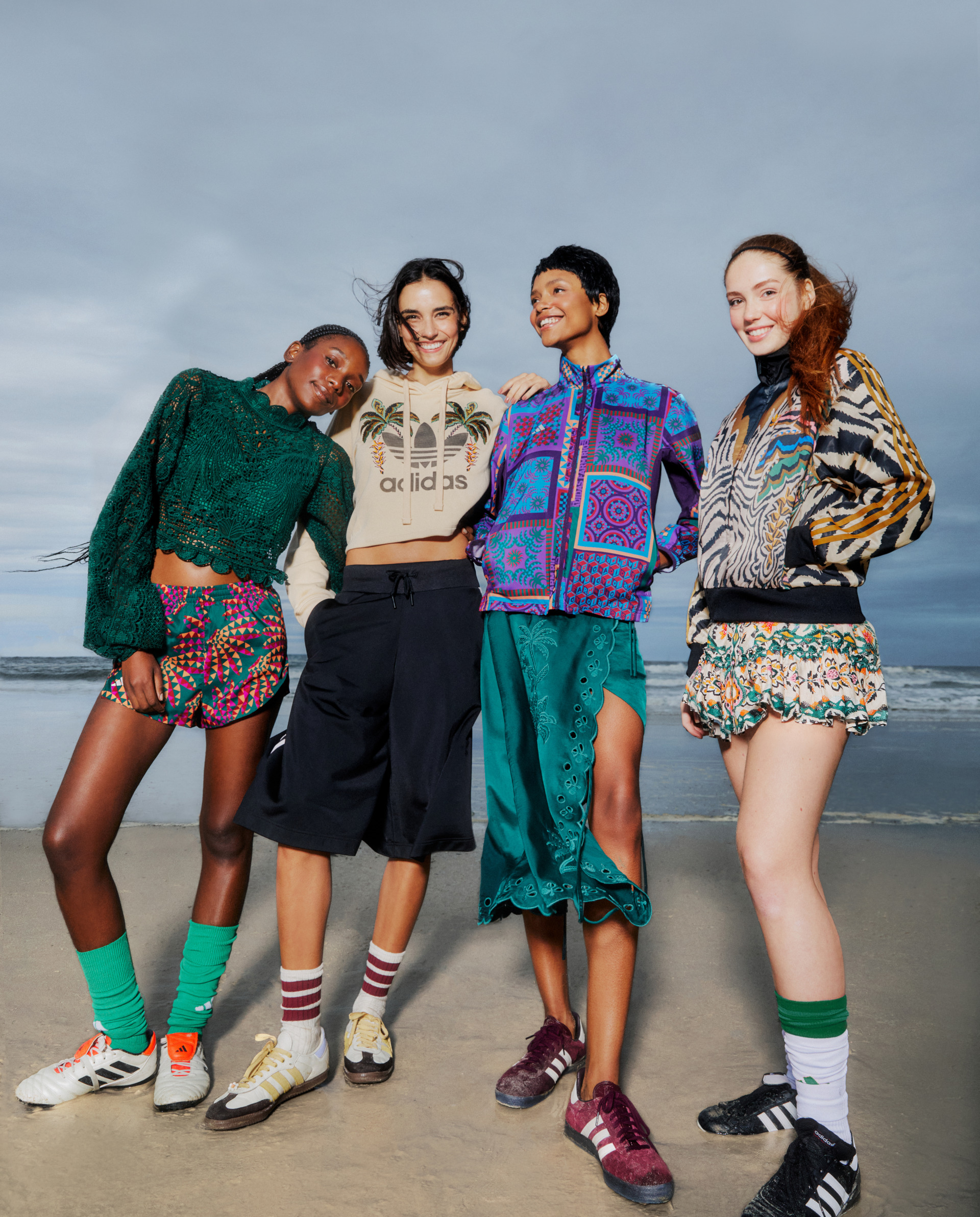 Four women stood on beach dressed in FARM Rio x Adidas clothing