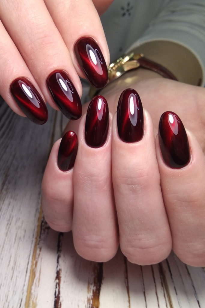 Close up of hands with cherry red nails and cat eye design