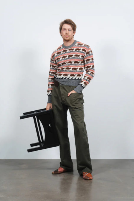 Man wearing jumper holding stool