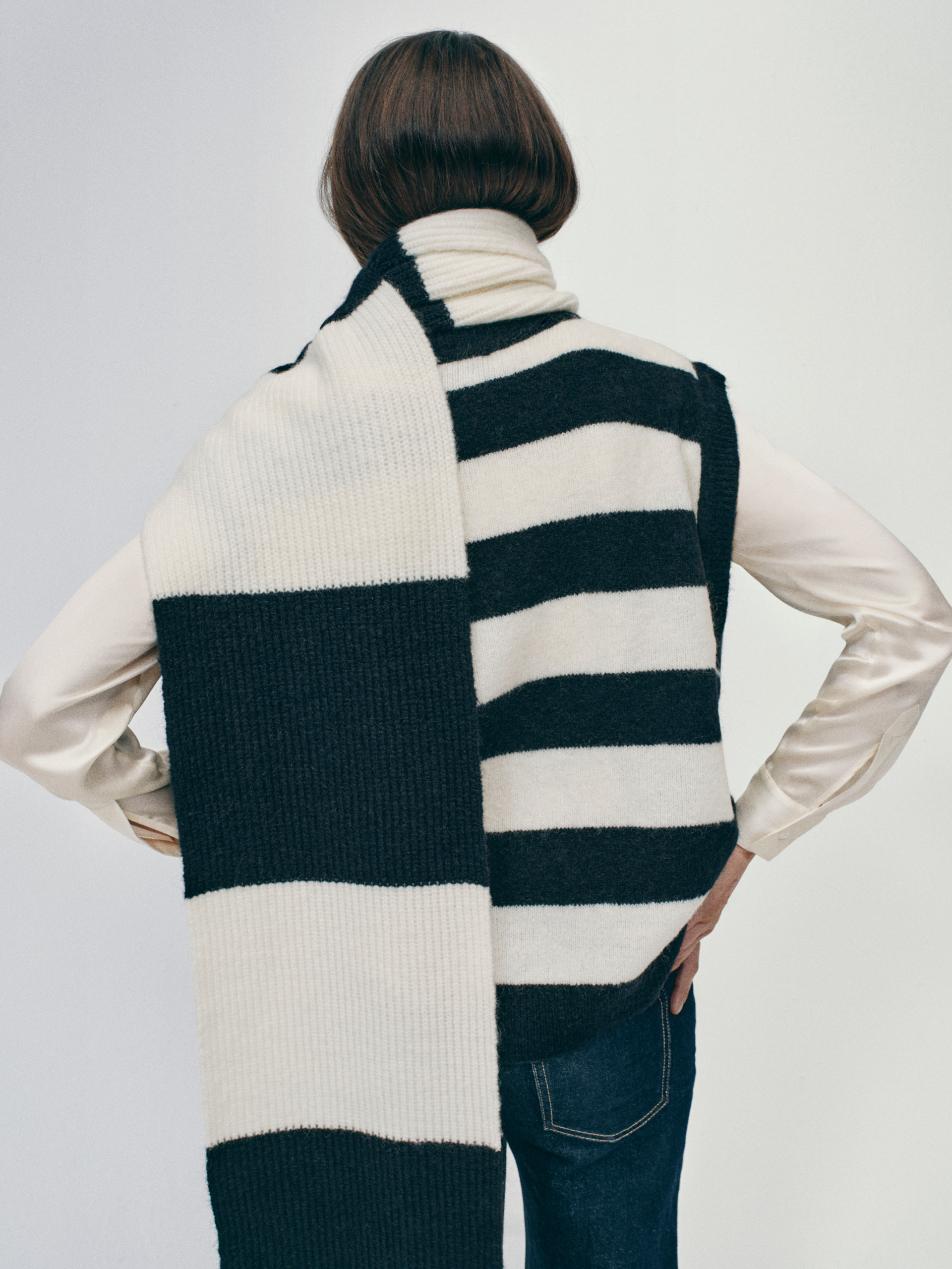 Woman's back wearing black and white sweater vet and scarf