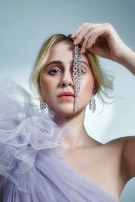 Maria Bakalova holds diamond jewellery in front of her eye