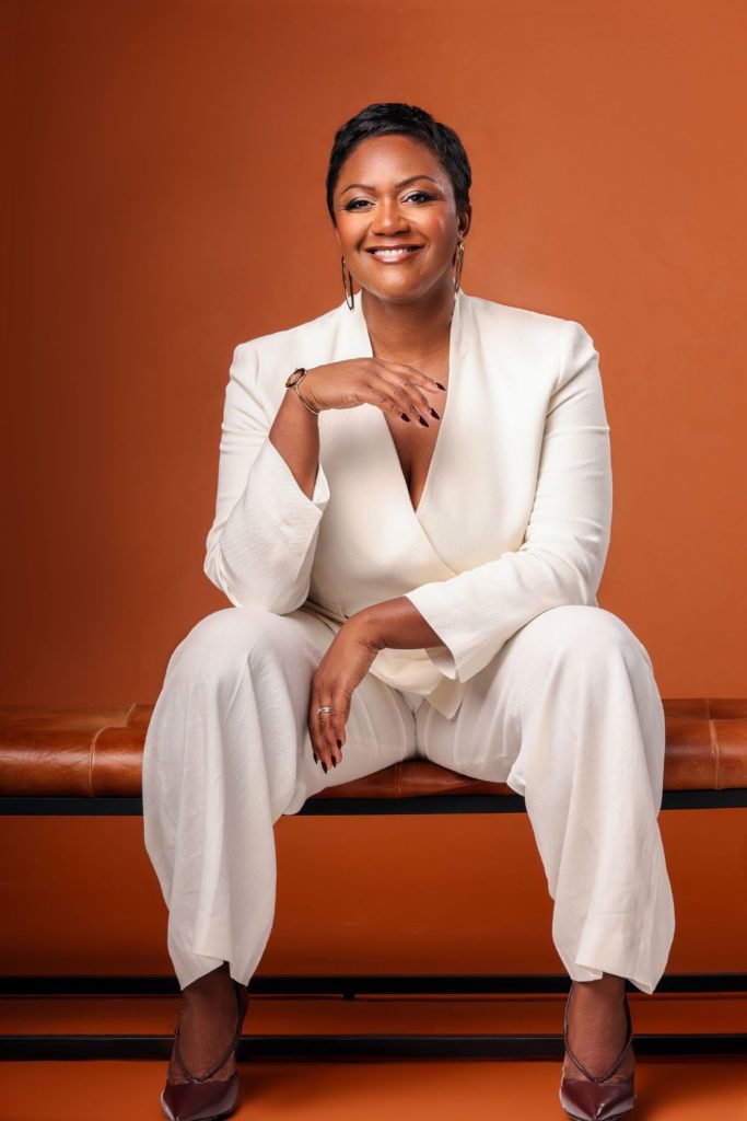 Designer Alex Dauley wearign a white suit against an orange backdrop