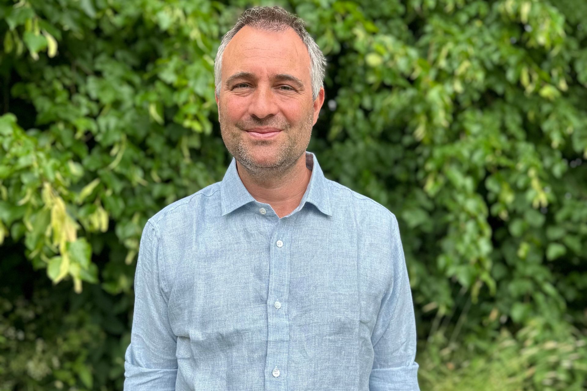 Ben Goldsmith standing in front of a leafy backdrop