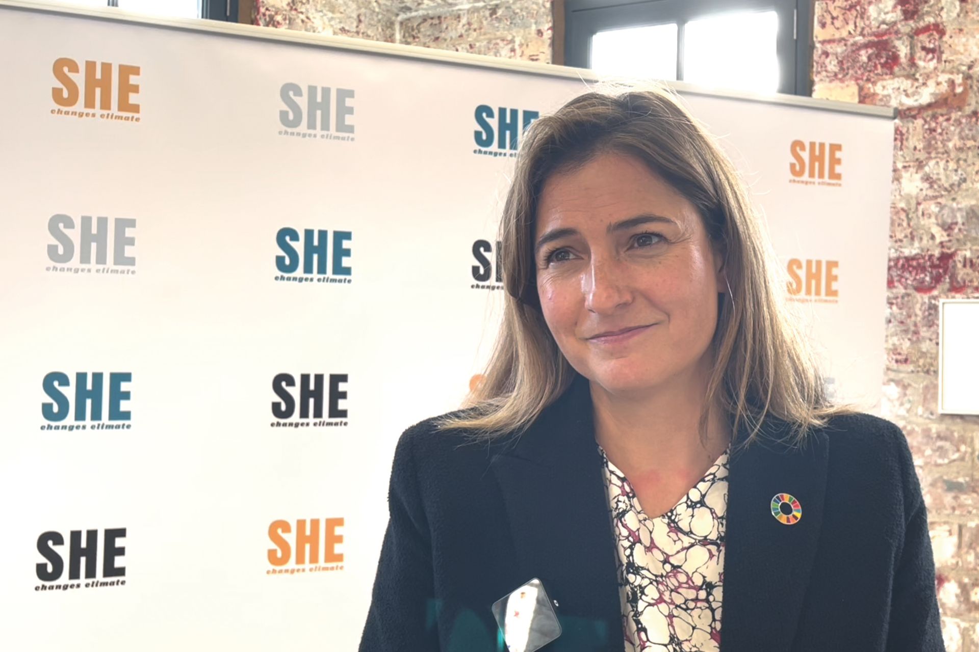 Bianca Pitt in front of a 'SHE changes climate' poster