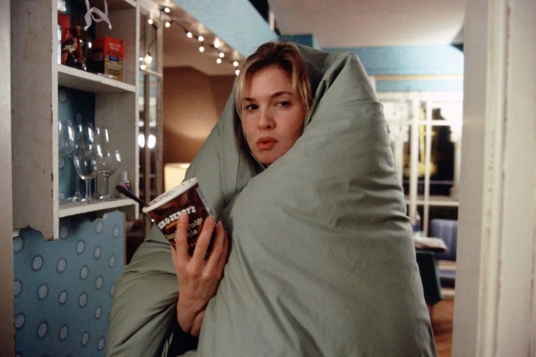 Bridget Jones in 'The Edge of Reason', wrapped in a grey duvet holding a tub of Ben & Jerry's ice cream.