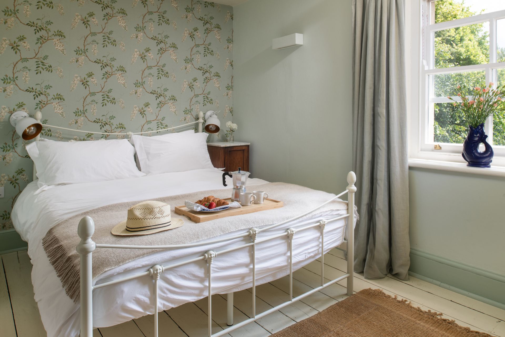 Bedroom with cream floral wallpaper and a white metal bedframe