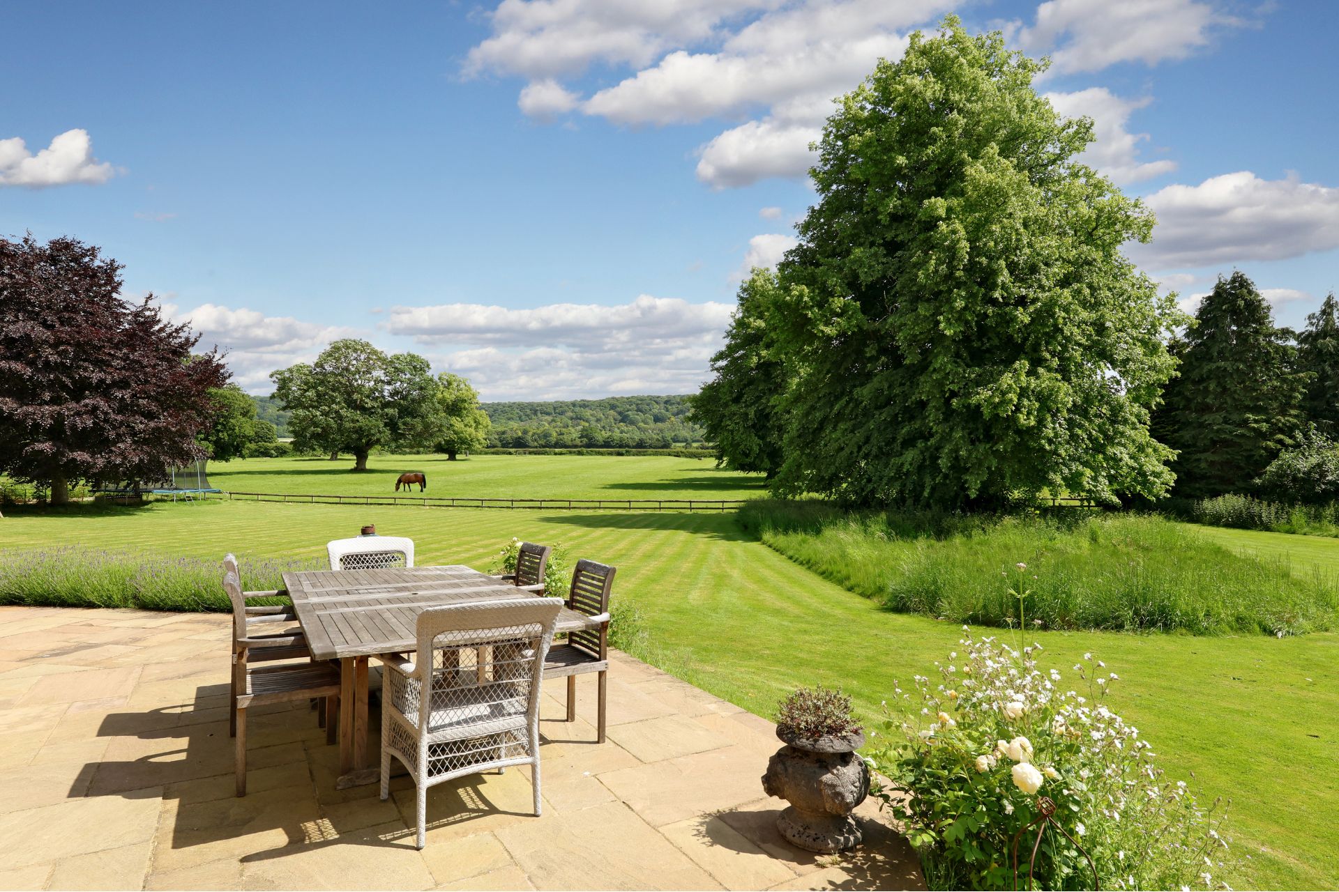 Garden with paved dining area and paddocks surrounding it