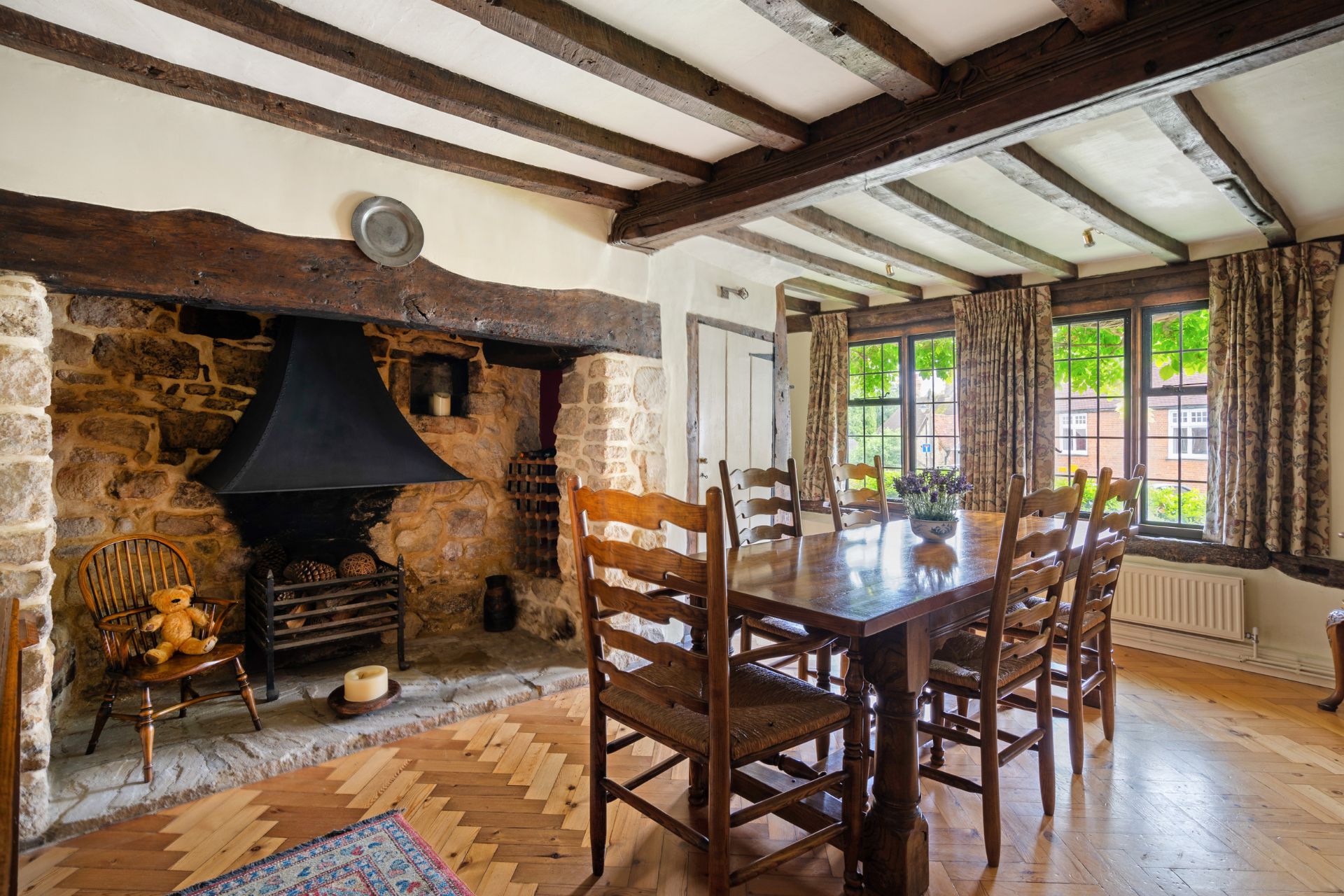 Dining room with wooden furniture, exposed beams and an inglenook fireplace.