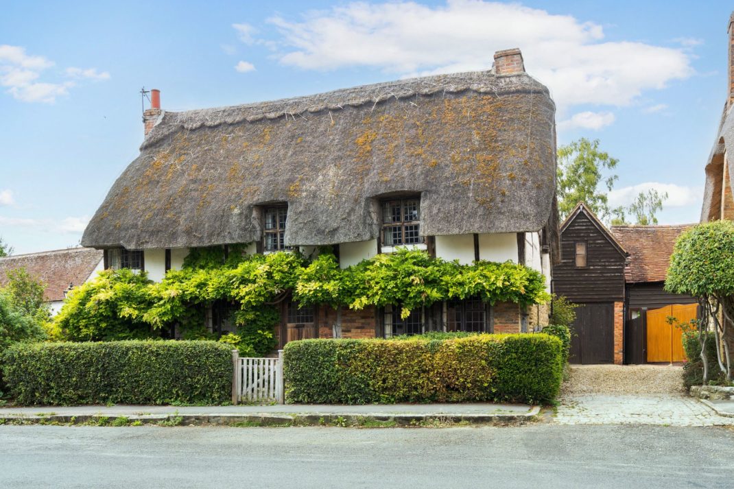 Thatched cottage with a box hedge and leaded windows.