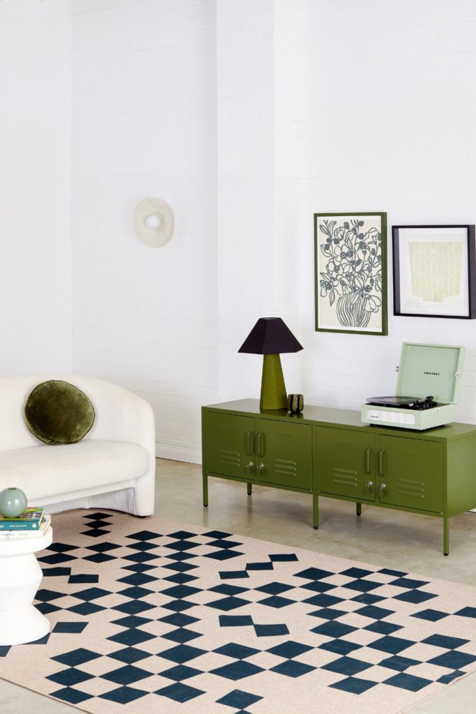 White room with black checkerboard rug, white sofa and olive green cabinet