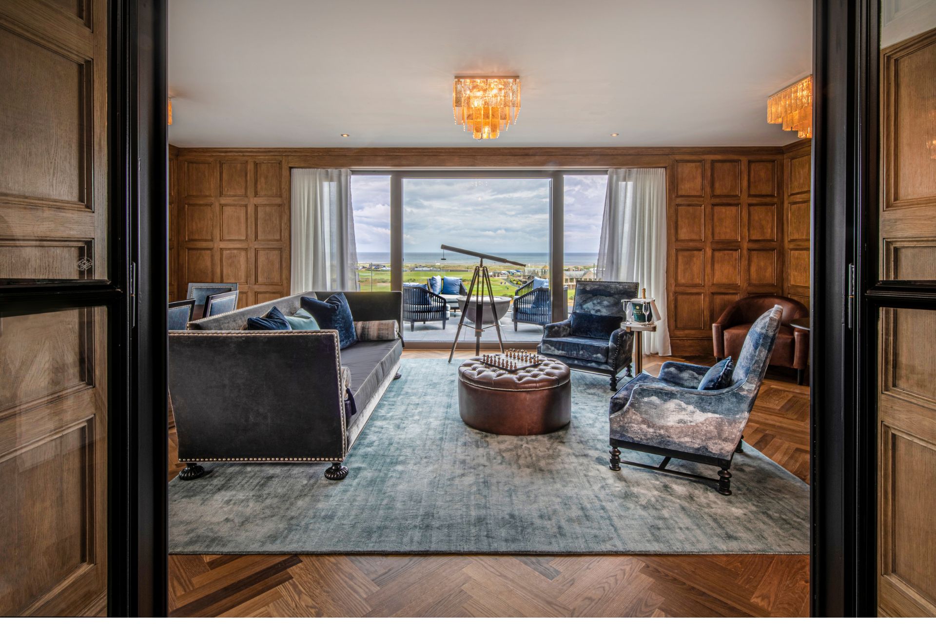 Hotel suite with wood-panelled walls, blue velvet sofas and a telescope