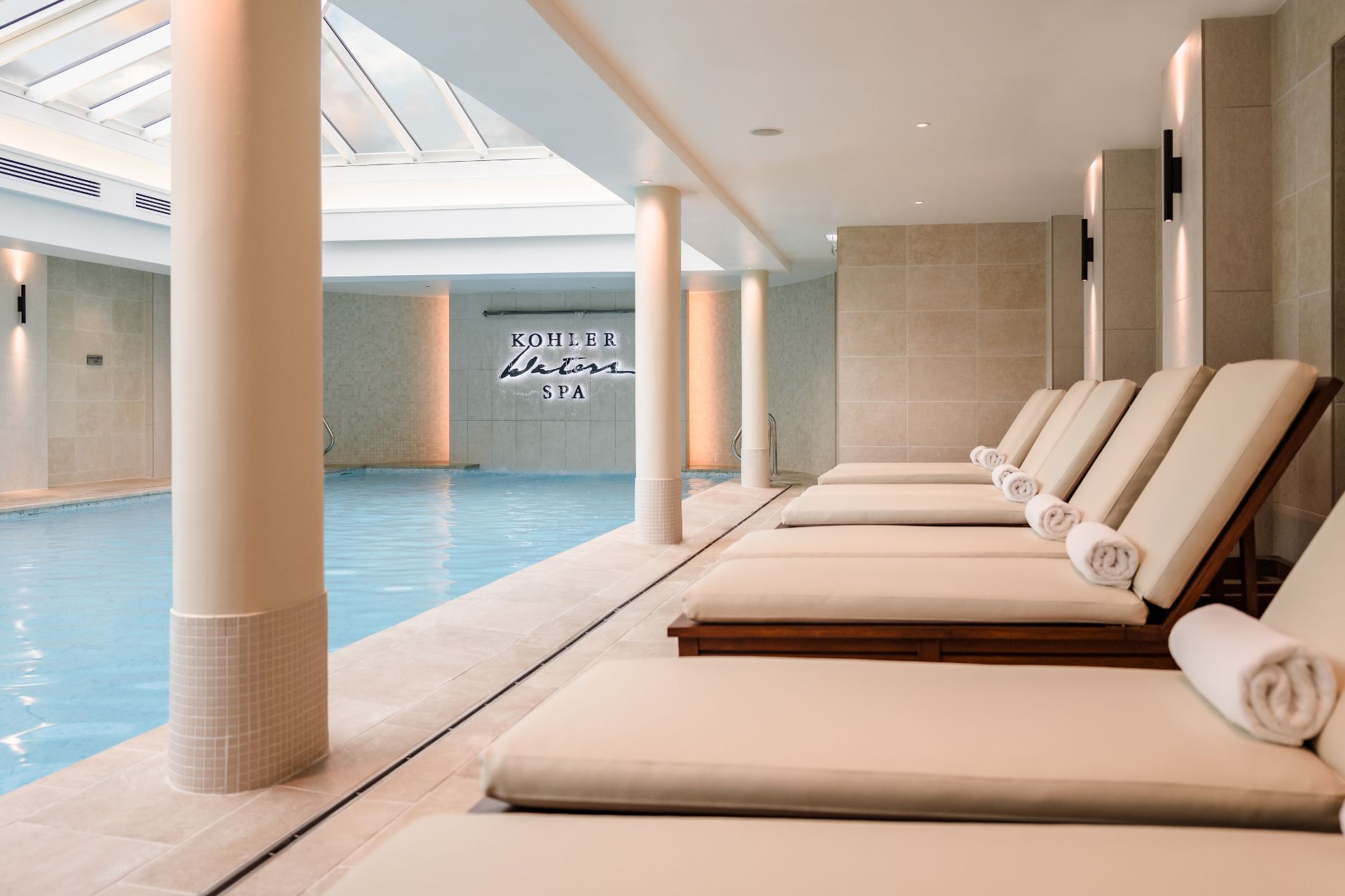 Indoor pool with marble columns and white sun loungers