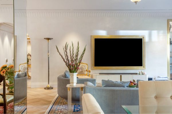 Living room with cornflower blue curved sofas and a gold-framed TV