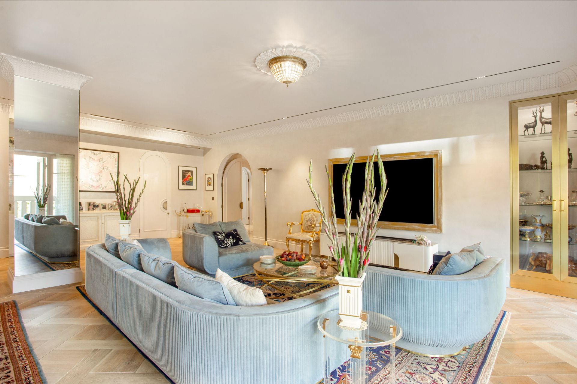Living room with bue curved sofas and a gold-framed TV