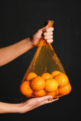 Hand holding a bag of oranges