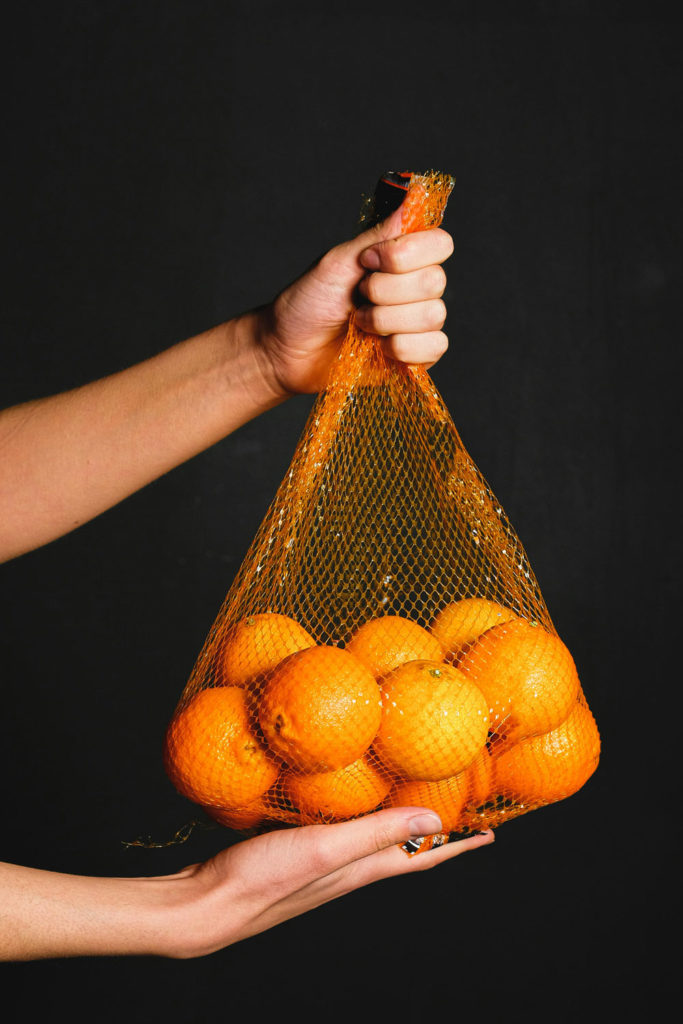Hand holding a bag of oranges