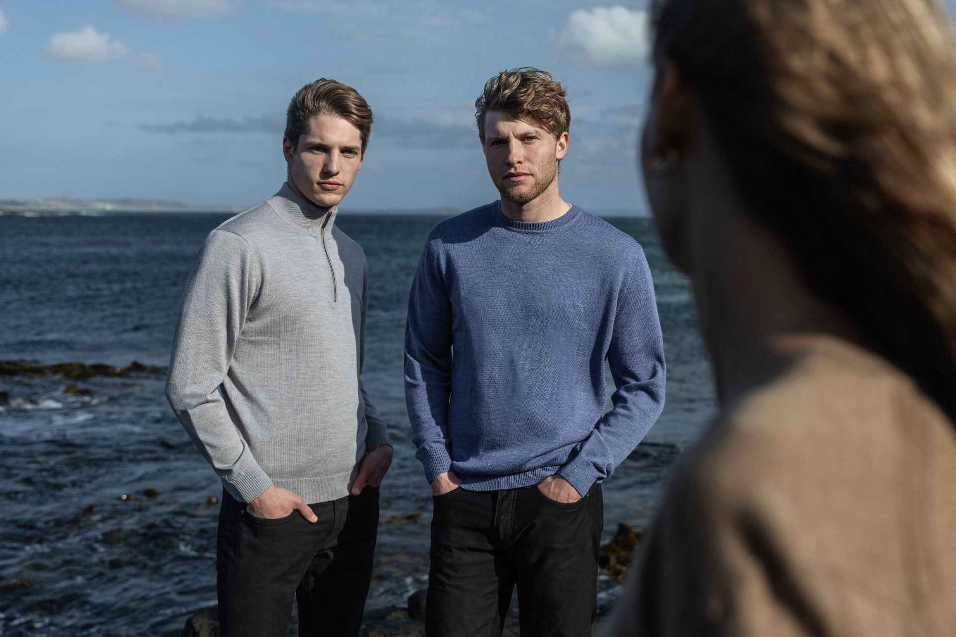 Rodd & Gunn models on a beach wearing blue and grey sweaters