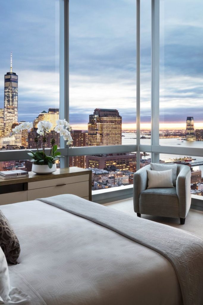 NYC hotel room with white linens and sweeping city views.
