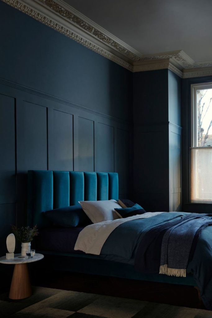 Teal bedroom with teal velvet headboard and blue bedsheets