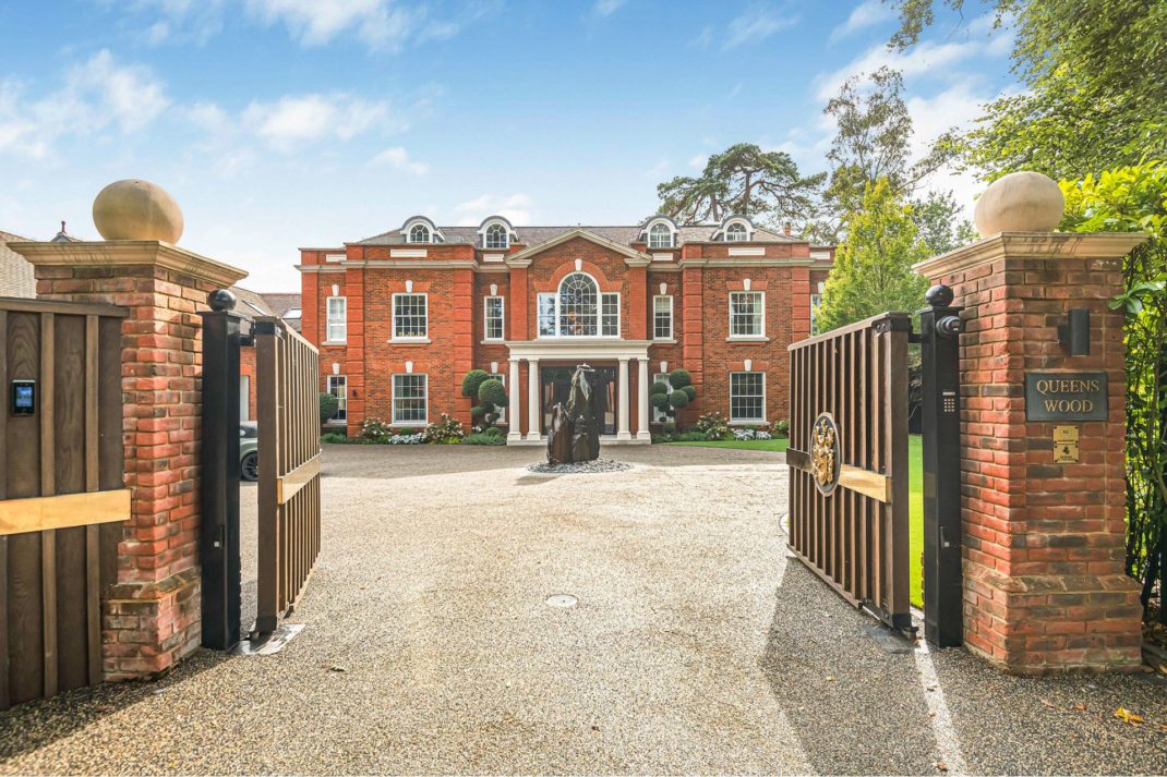 Large red brick mansion with a gated driveway