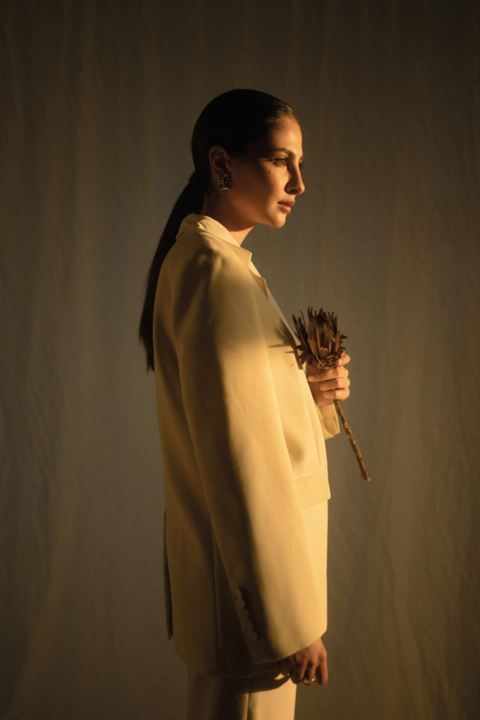 Woman in suit holding flower | sustainable partywear