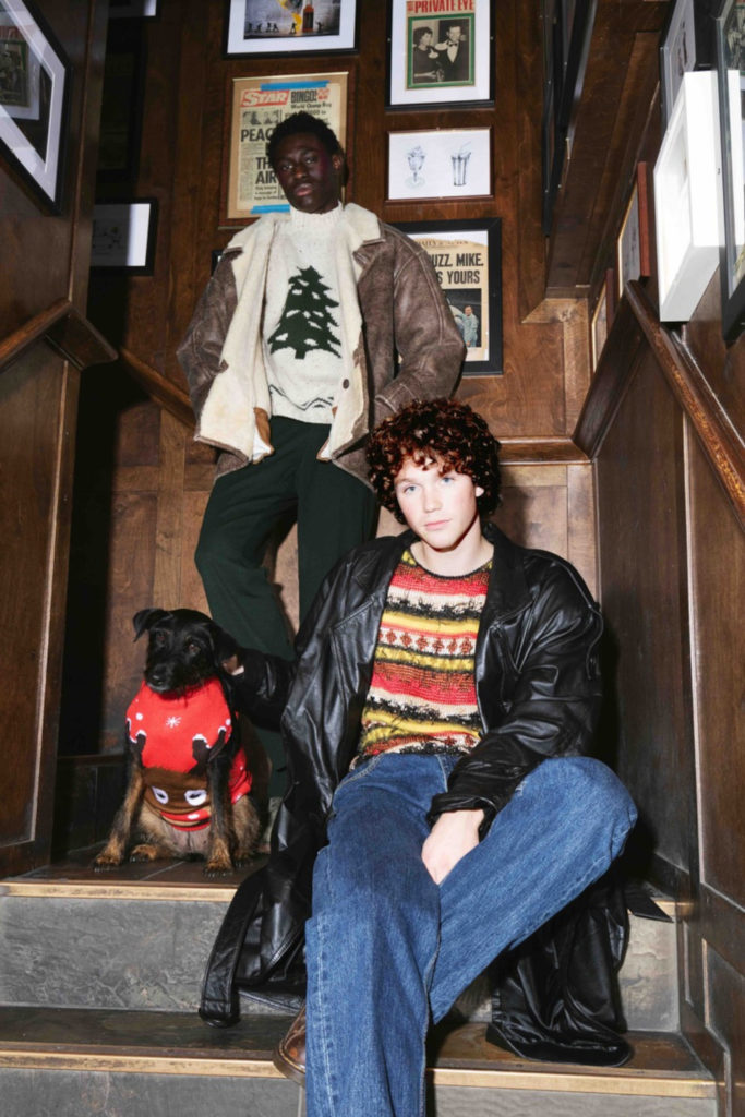 Two men and a dog sat in steps in Christmas jumpers | Beyond Retro winter pop-up