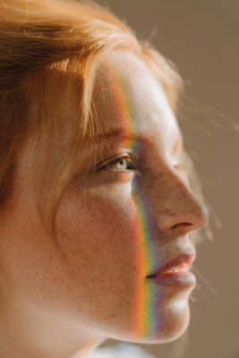 Close up of woman's face with rainbow light