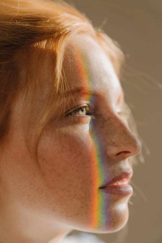 Close up of woman's face with rainbow light