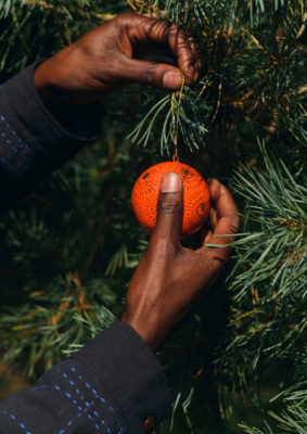 A hand affixes a bauble to a tree
