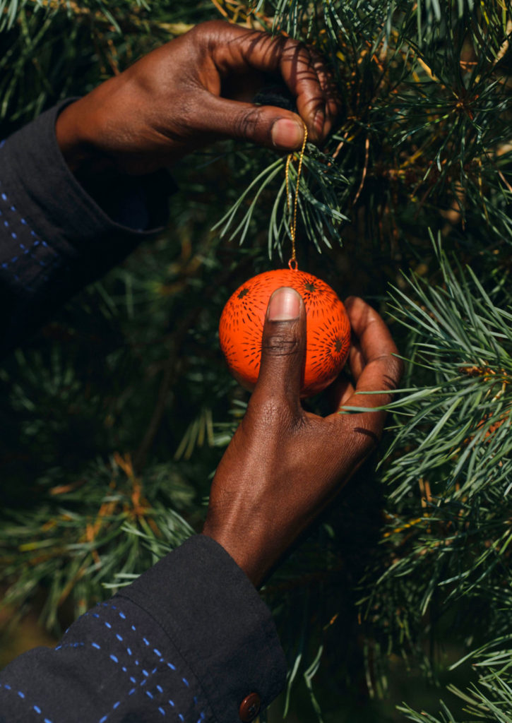 A hand affixes a bauble to a tree