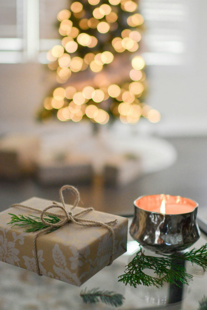 Present and candle on table in front of Christmas tree
