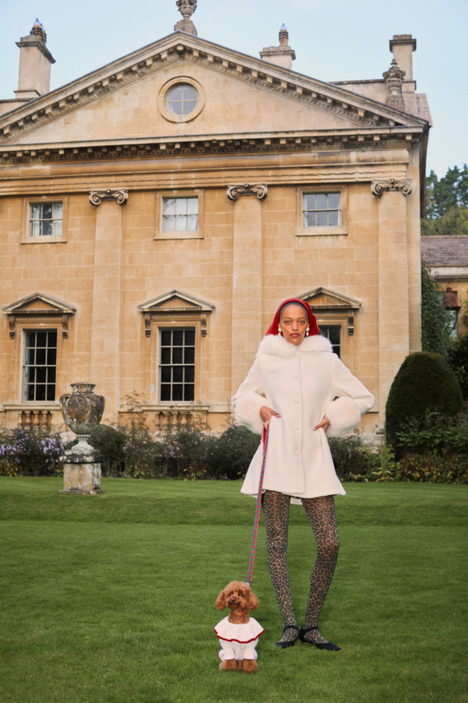Woman walking dog outside manor house