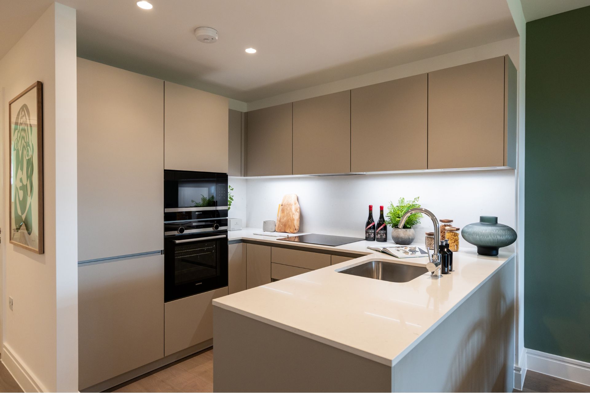 Modern kitchen with taupe cabinets, white counters and a built-in oven