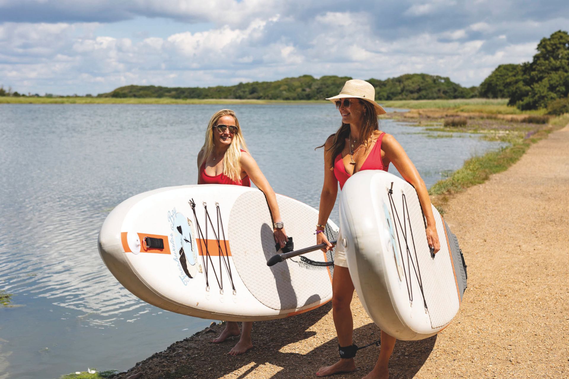 Two women walking with paddle boards