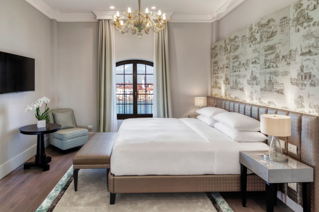 Hotel site with cream walls, a chandelier and a green and white patterned feature wall