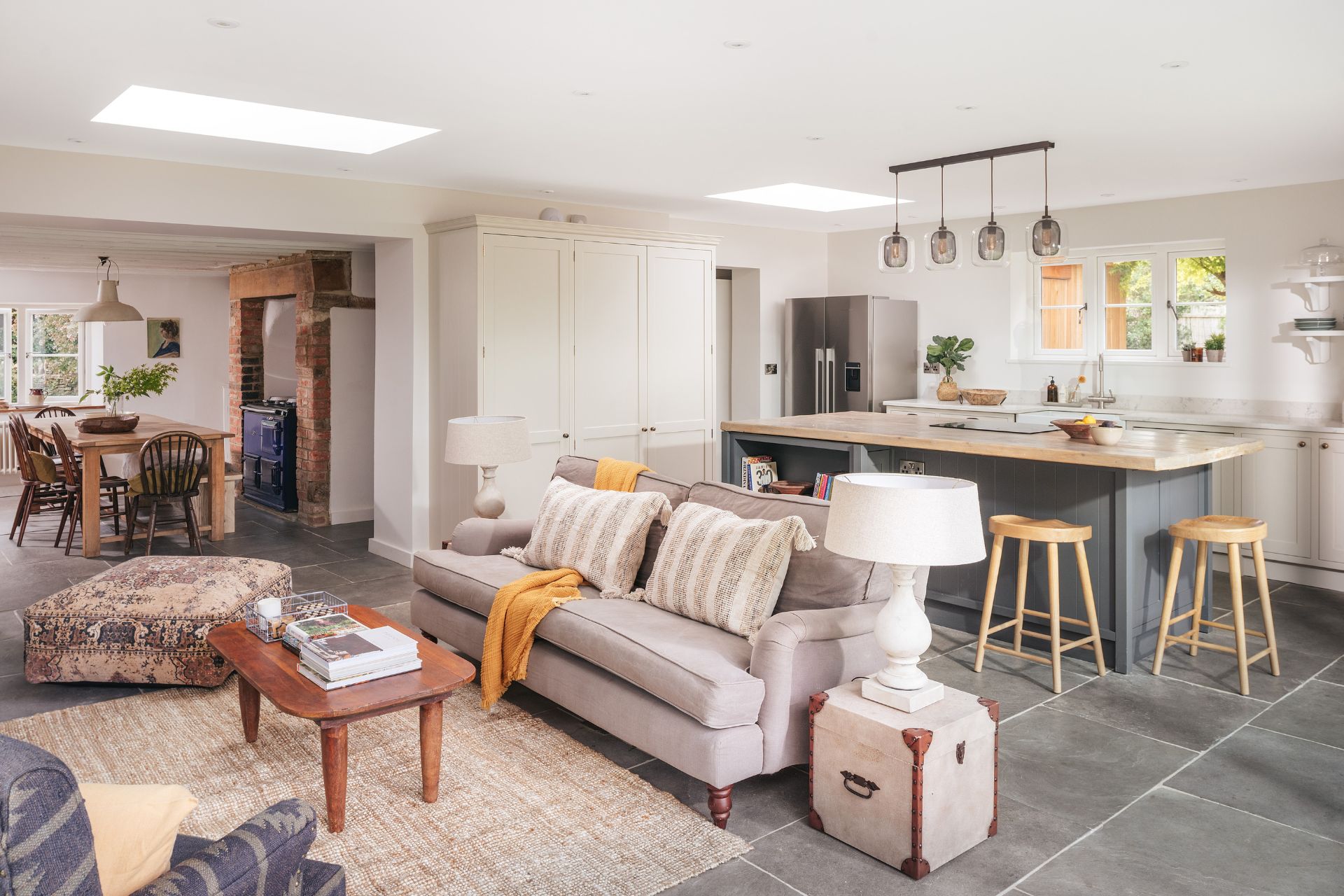 Open plan kitchen with cream sofas and a grey central island with wooden countertops