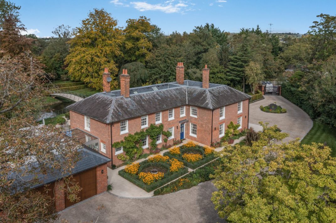 Aerial view of red brick Georgian house with landscaped gardens and a curved driveway