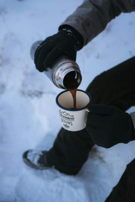 Pouring coffee into a mug in the snow