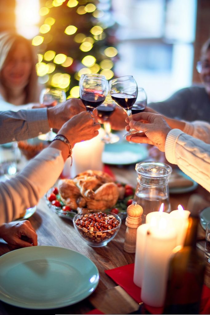 People toasting with red wine glasses at a Christmas dinner