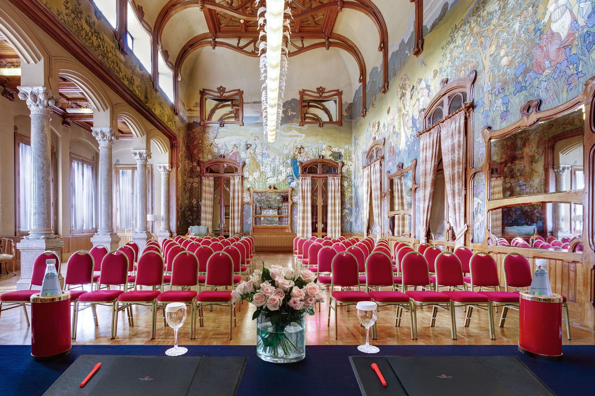 Large hall with frescoed walls, wooden beams and stone arches