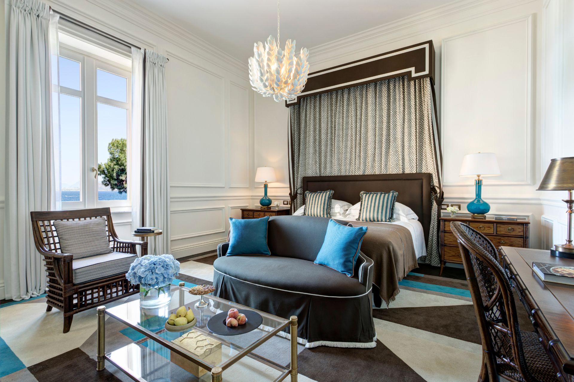 Hotel room with a pale green canopy bed and curved blue chaise longue