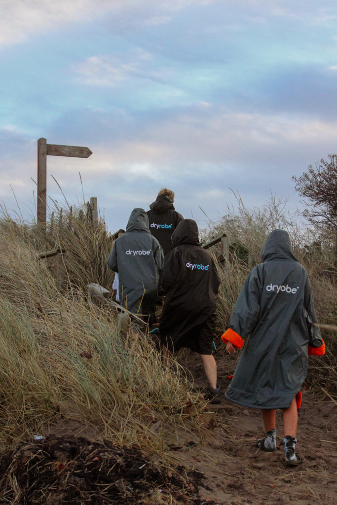 Swimmers wearing dryrobes in the dunes