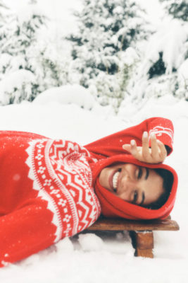 Woman lying in snow wearing red Christmas jumper