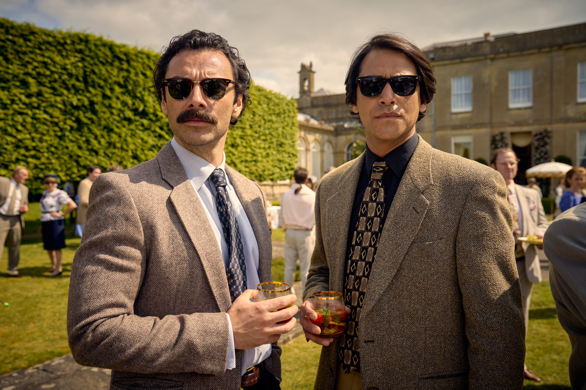 Aidan Turner as Declan O’Hara & Luca Pasqualino as Basil ‘Bas’ Baddingham in Rivals.