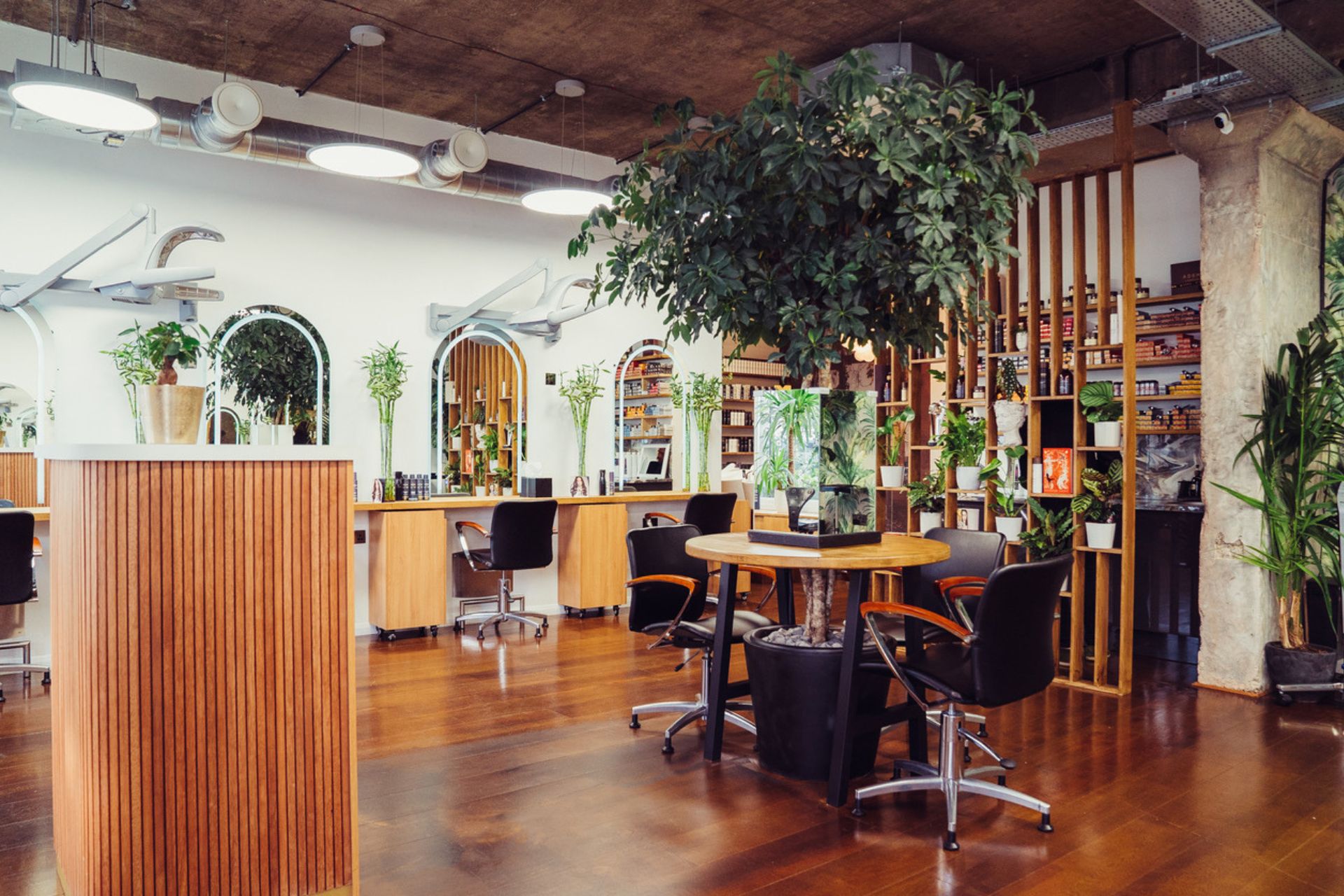 Hair salon with wooden floors, black leather chairs and hanging plants