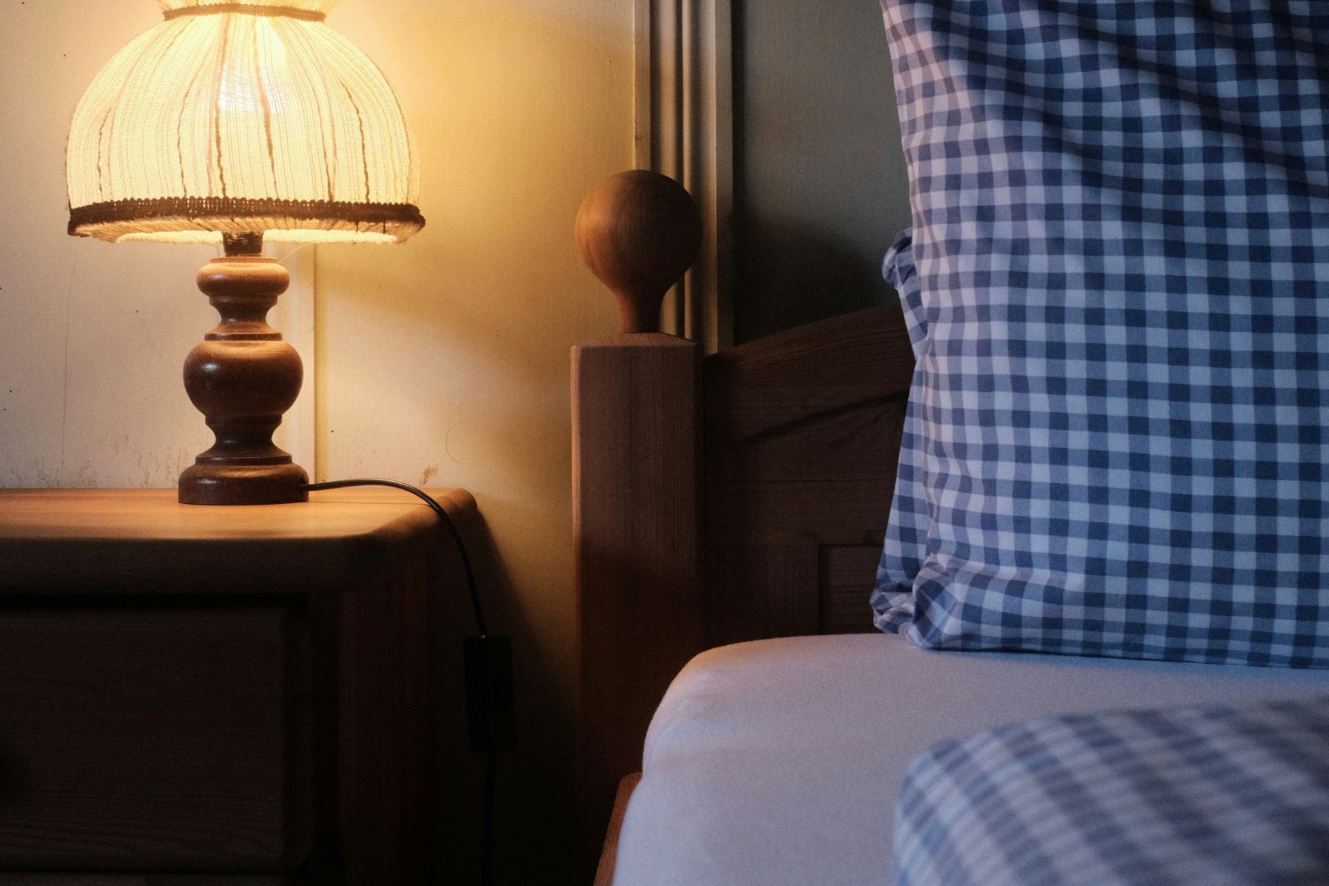 Bedroom with blue gingham sheets and a bedside lamp